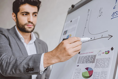 Neue Mitarbeitende: Kümmern sich Unternehmen zu wenig um Sie? 48 Ein junger Mann in einem Anzug schaut mit ernster Miene auf ein Flipchart mit Diagrammen. Die Studie über das Onboarding für neue Mitarbeitende ist erschreckend.